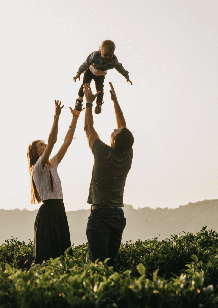 Photo d'une famille en pleine nature avec deux parents jouants avec leur enfant